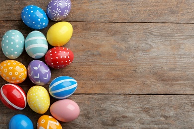 Flat lay composition of painted Easter eggs on wooden table, space for text