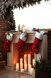 Photo of Decorative fireplace with Christmas stocking and gifts in stylish room interior