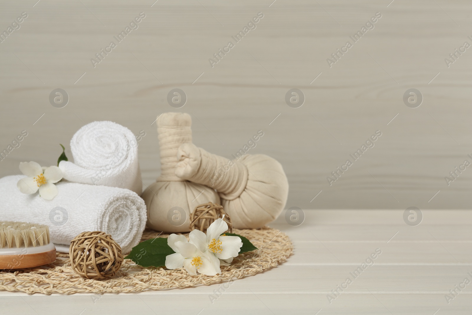 Photo of Composition with beautiful jasmine flowers, towels and herbal bags on white wooden table, space for text