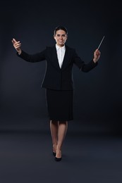 Photo of Happy young conductor with baton on dark background
