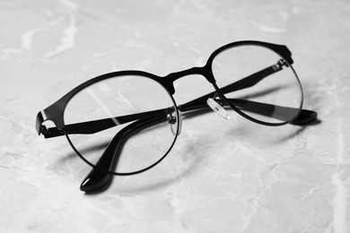 Photo of Glasses in stylish frame on grey marble table, closeup