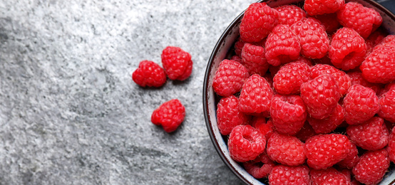 Photo of Delicious fresh ripe raspberries in bowl on grey table, flat lay. Space for text