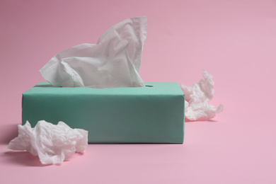 Photo of Box of paper tissues and used crumpled napkins on pink background