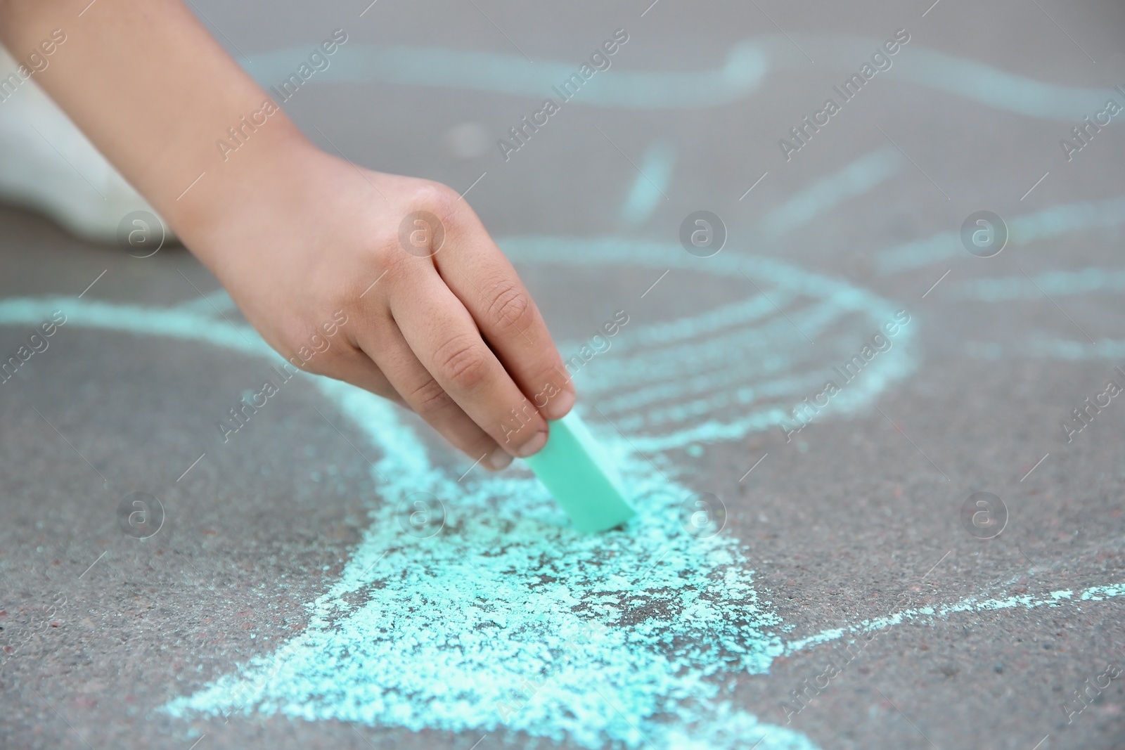 Photo of Little child drawing with chalk on asphalt, closeup