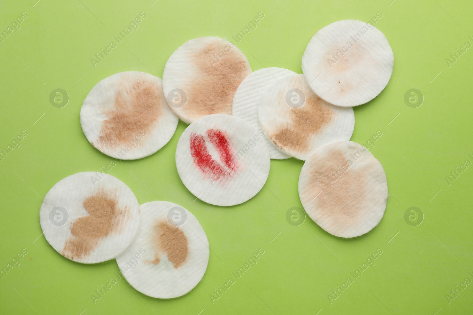 Photo of Dirty cotton pads after removing makeup on green background, flat lay