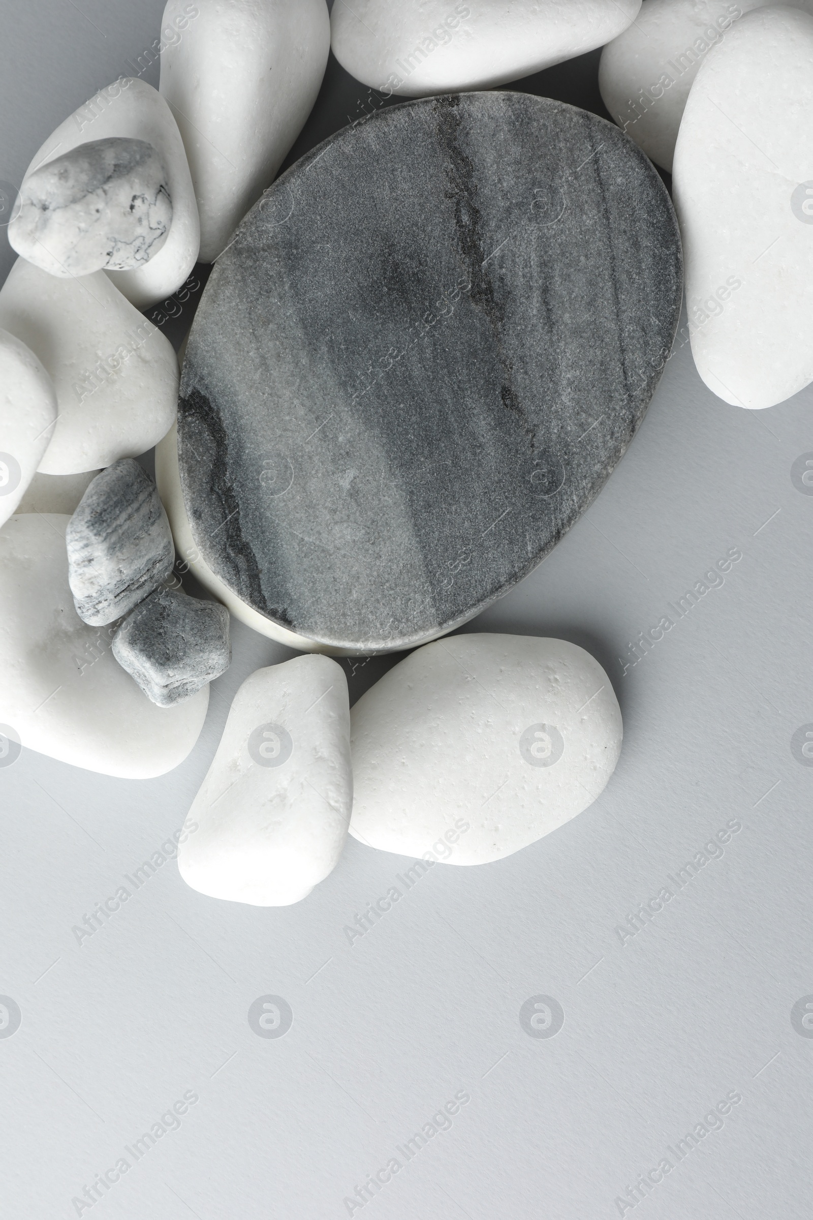 Photo of Presentation for product. Stone podium and pebbles on light grey background, top view. Space for text