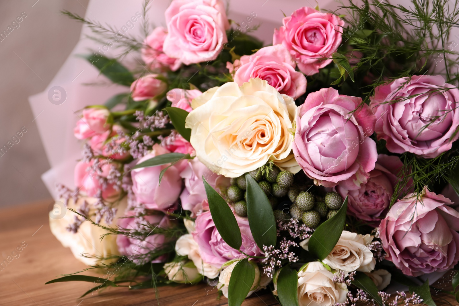 Photo of Beautiful bouquet with roses on wooden table, closeup