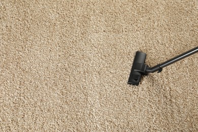 Removing dirt from beige carpet with modern vacuum cleaner, above view. Space for text