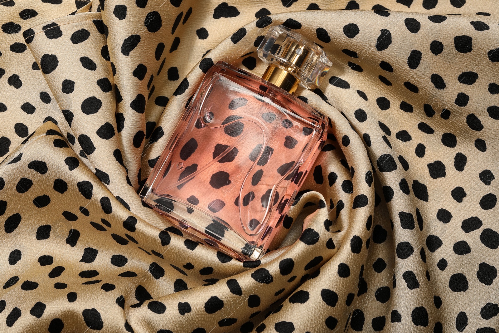 Photo of Luxury perfume in bottle on fabric with leopard pattern, top view