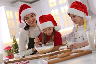 Photo of Mother with her cute little children making Christmas cookies in kitchen