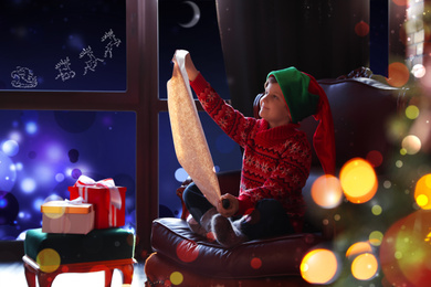 Image of Cute little boy with wish list to Santa Claus near window at home. Christmas holiday