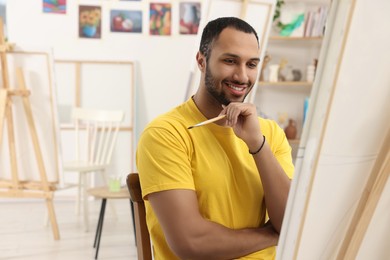 Photo of Young man painting with brush in studio. Creative hobby