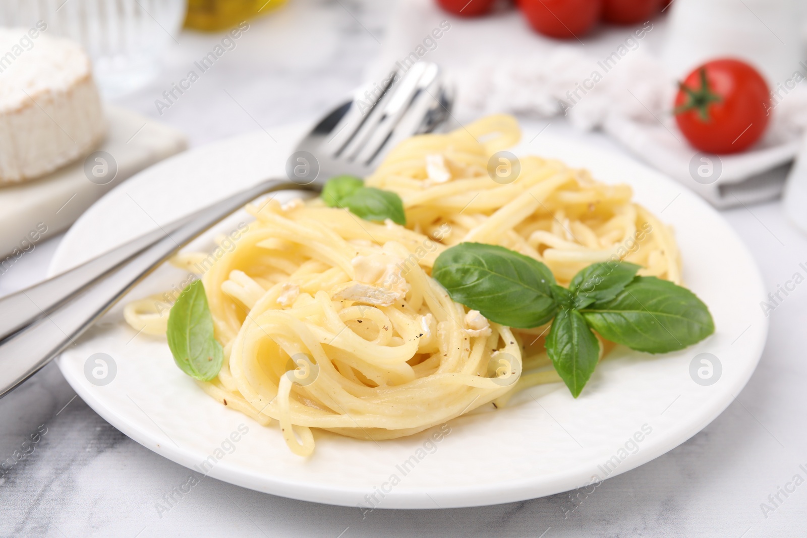 Photo of Delicious pasta with brie cheese and basil leaves on marble table, closeup