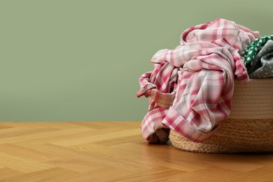 Photo of Laundry basket with clothes near light green wall. Space for text