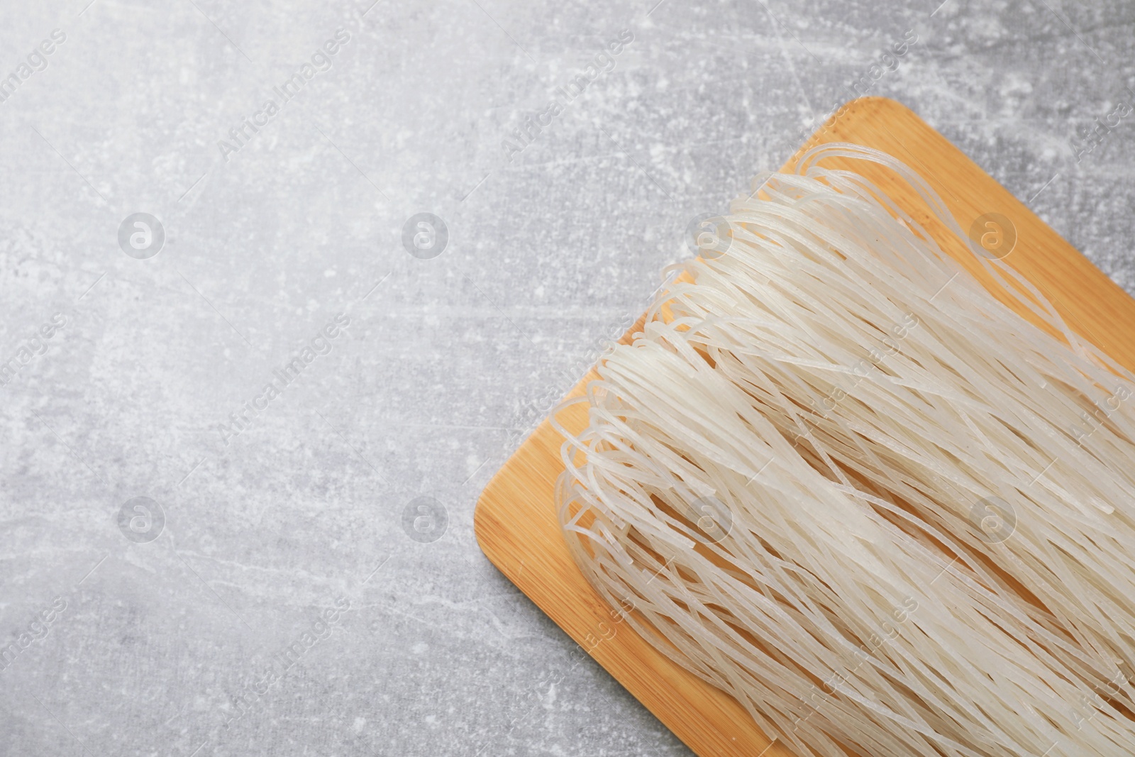 Photo of Uncooked rice noodles on light grey table, flat lay. Space for text