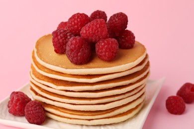 Photo of Stack of tasty pancakes with raspberries on pink background, closeup
