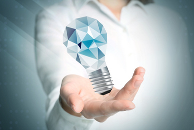 Image of Idea concept. Businesswoman demonstrating glowing light bulb illustration on light background, closeup