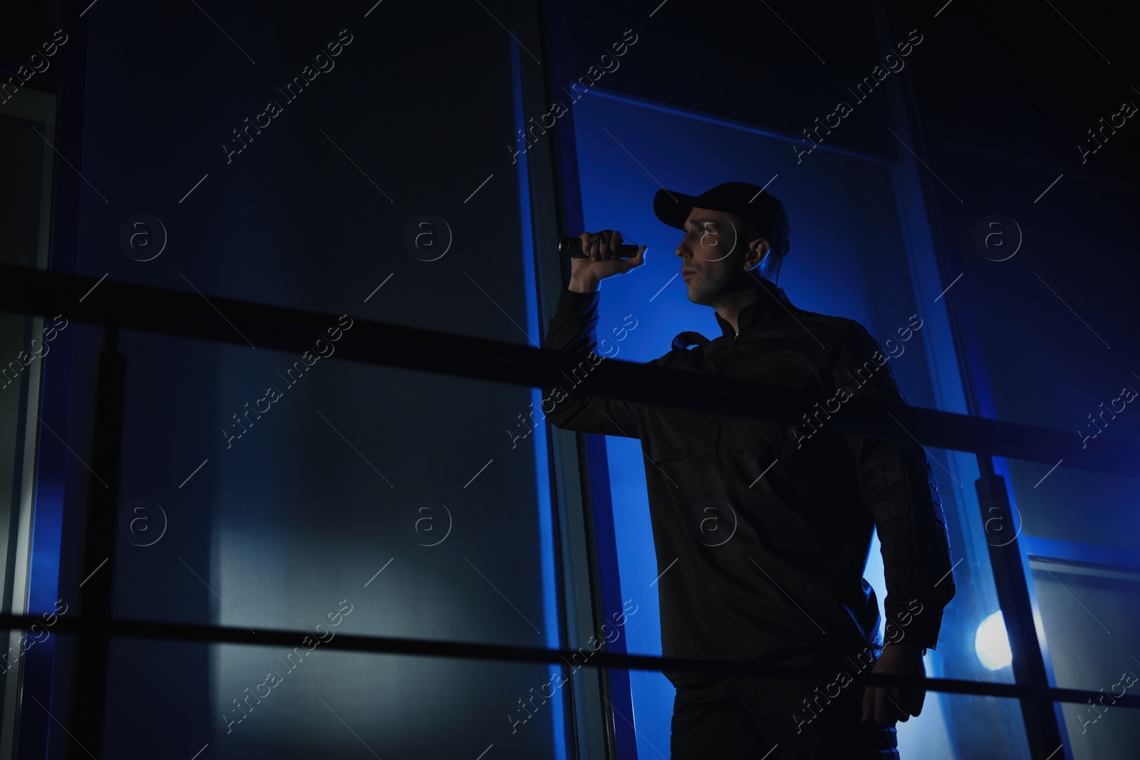 Photo of Male security guard with flashlight in dark room