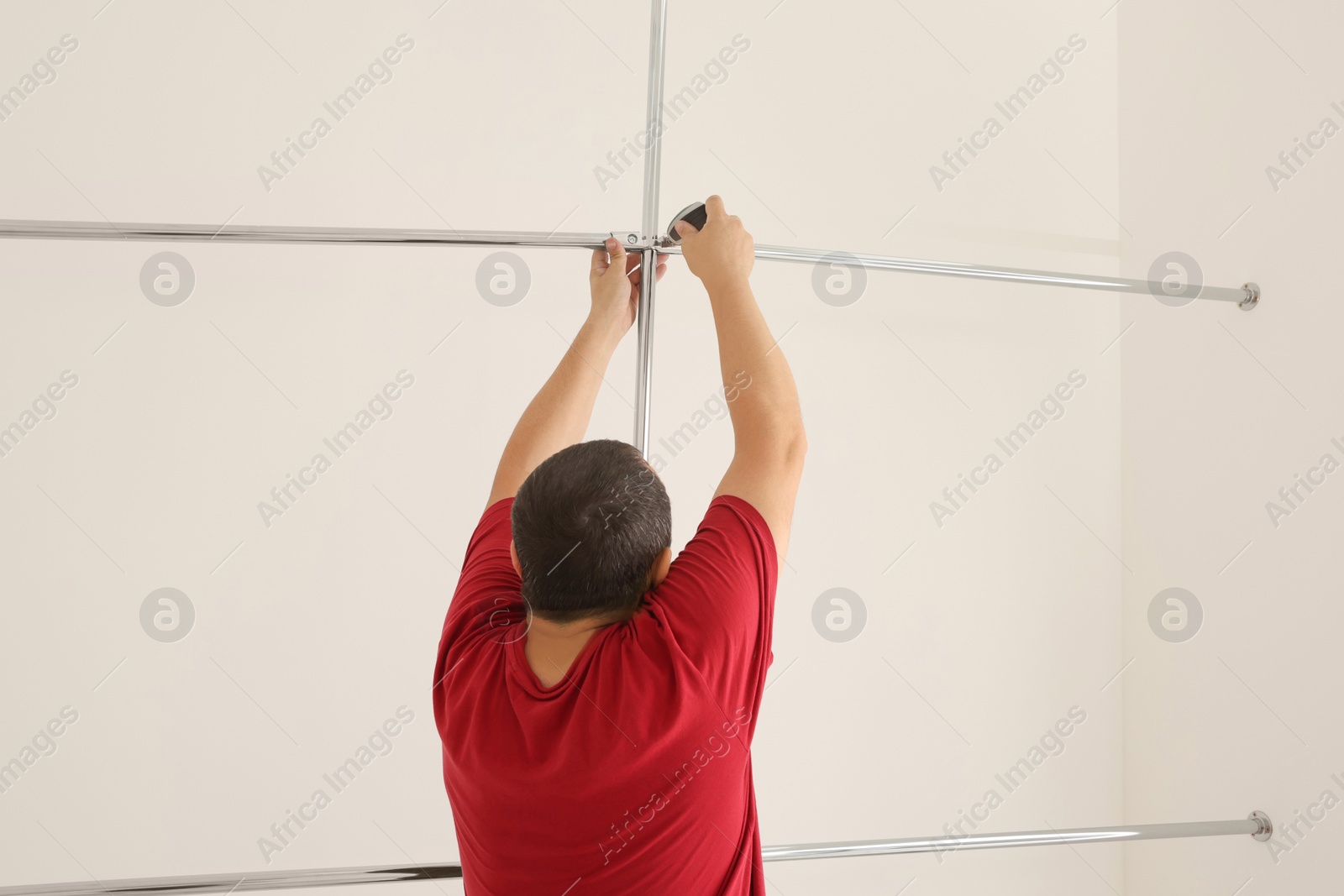 Photo of Worker installing new metal pipes indoors, back view