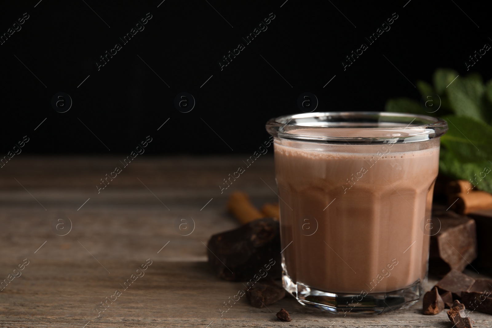 Photo of Glass of delicious hot cocoa on wooden table. Space for text