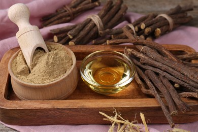 Photo of Dried sticks of licorice root, powder and essential oil on table