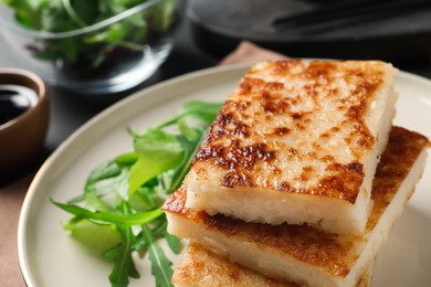 Photo of Delicious turnip cake with arugula served on table, closeup