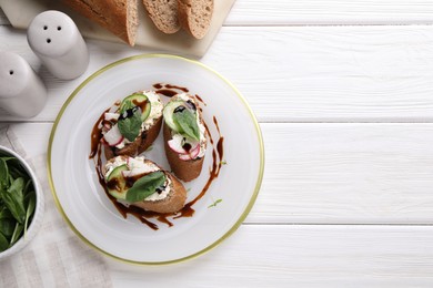 Photo of Delicious bruschettas with cream cheese, vegetables, balsamic vinegar and ingredients on white wooden table, flat lay. Space for text