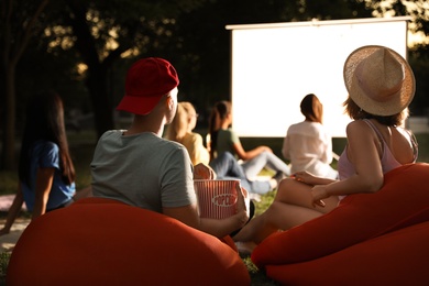 Photo of Young couple with popcorn watching movie in open air cinema. Space for text