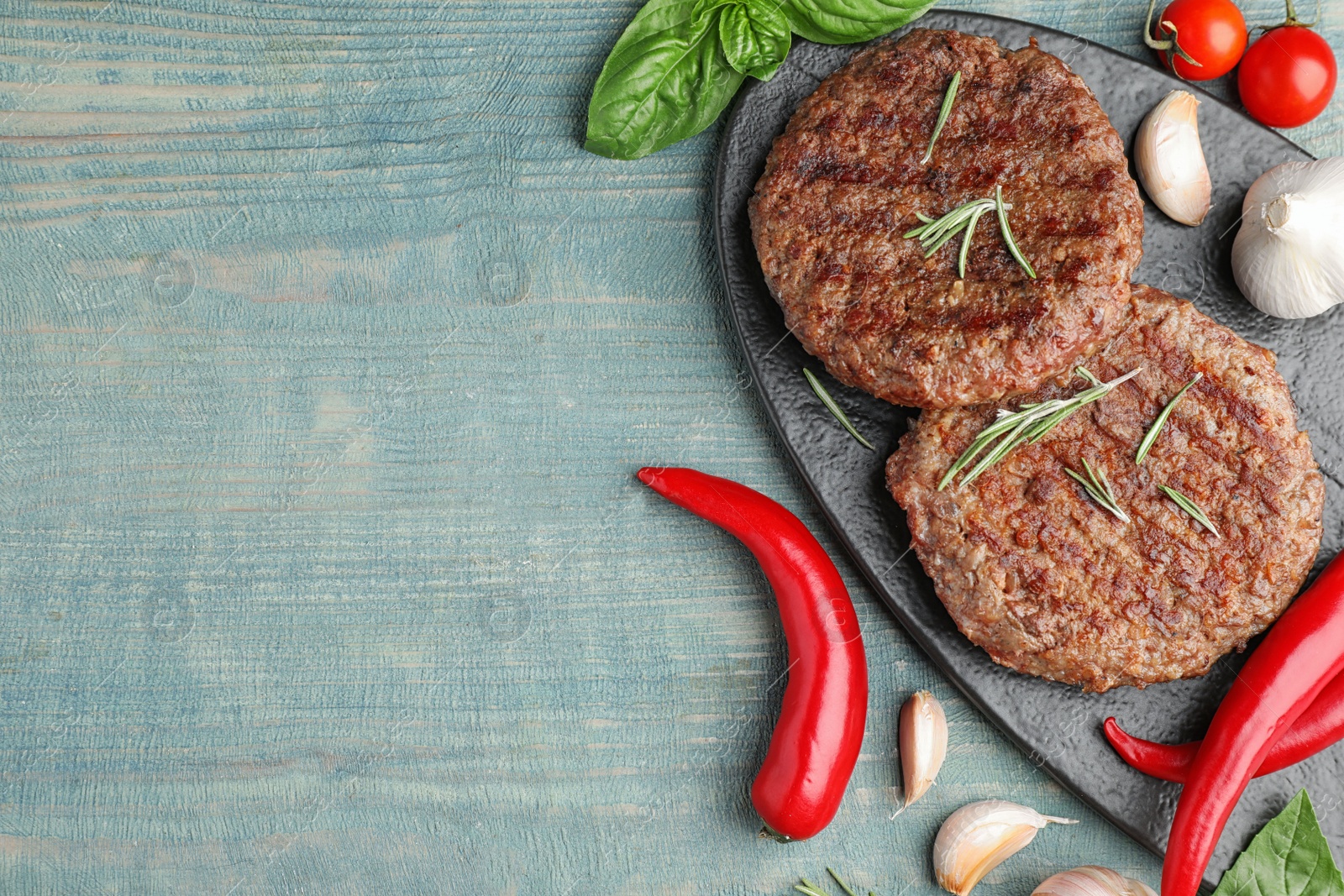 Photo of Flat lay composition with grilled meat cutlets for burger on blue wooden table. Space for text