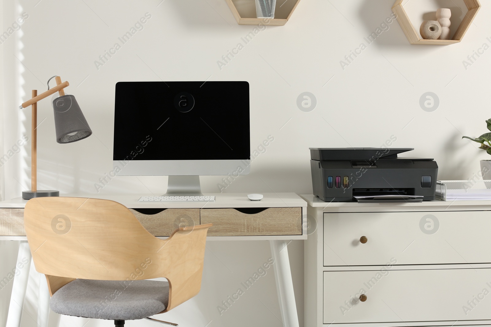 Photo of Stylish workplace with modern computer, printer and lamp