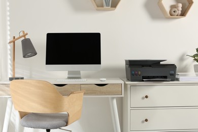 Photo of Stylish workplace with modern computer, printer and lamp