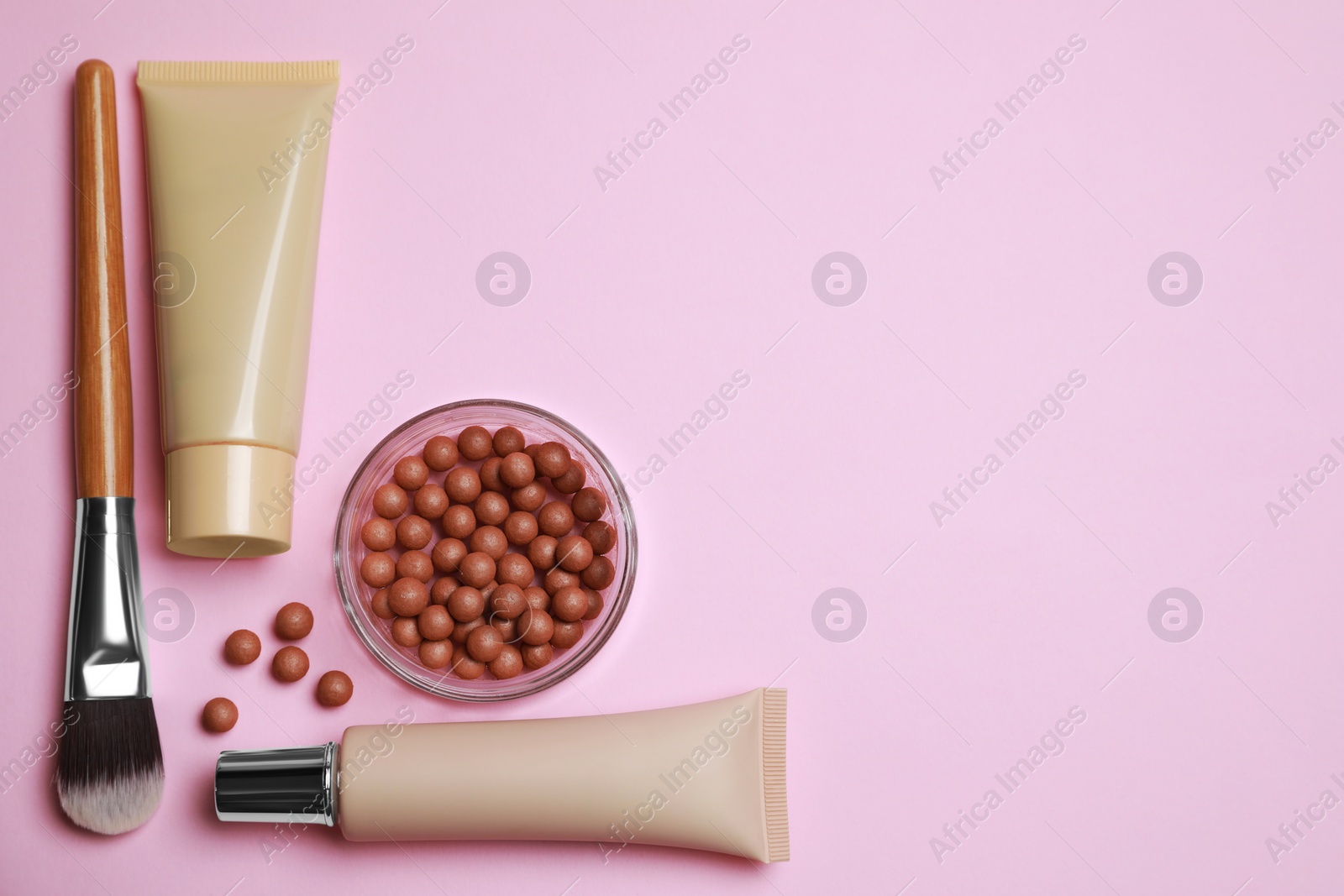 Photo of Face powder balls and other decorative cosmetic products on pink background, flat lay. Space for text