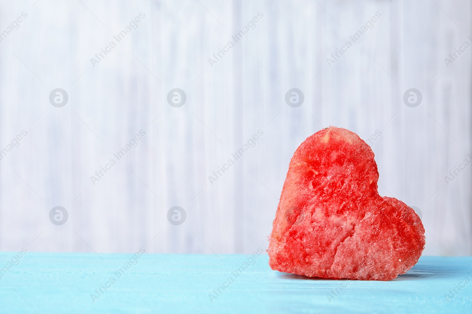 Photo of Heart shaped watermelon slice on table against light background