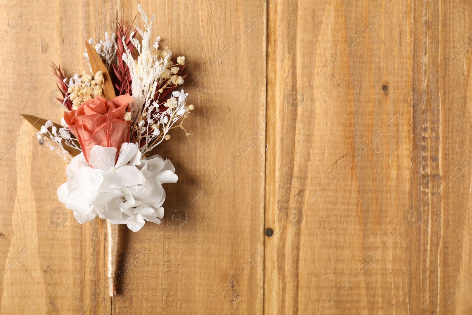 Photo of Stylish boutonniere on wooden table, top view. Space for text