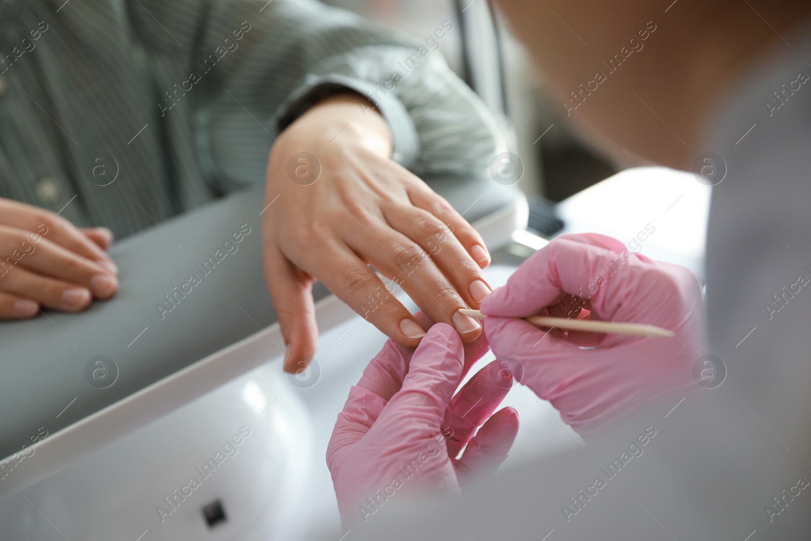 Photo of Professional manicurist working with client in beauty salon, closeup