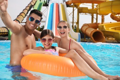 Photo of Happy family taking selfie in swimming pool at water park