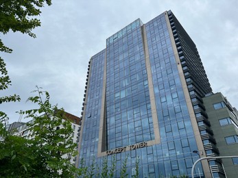 Photo of WARSAW, POLAND - JULY 13, 2022: Beautiful building and green trees against cloudy sky, low angle view