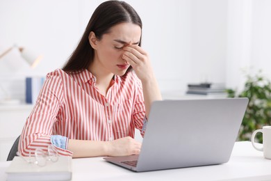 Photo of Woman suffering from headache at workplace in office