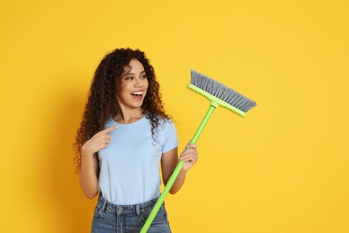 African American woman with green broom on orange background