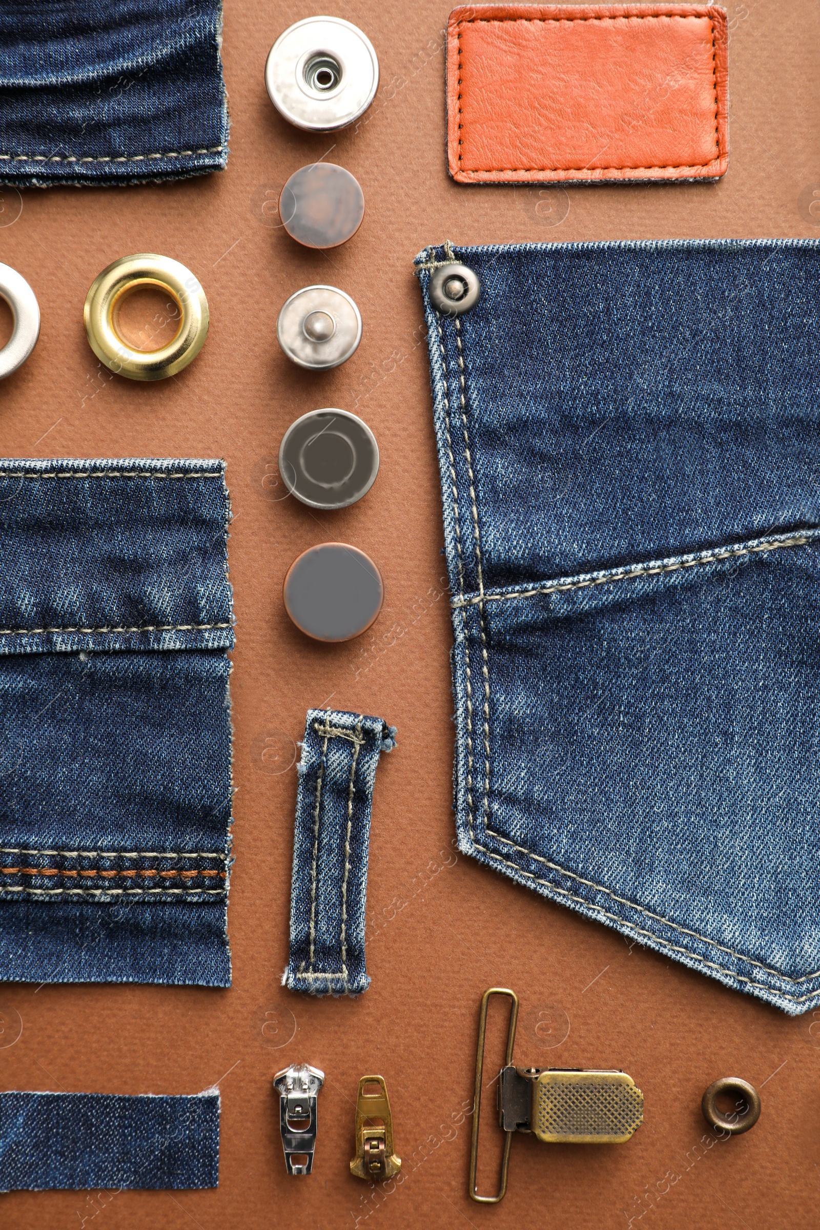 Photo of Flat lay composition with garment accessories and cutting details for jeans on brown background