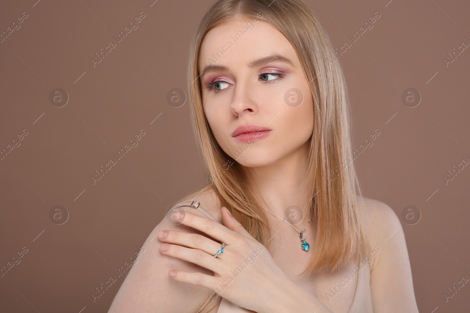 Photo of Beautiful young woman with elegant jewelry on light brown background