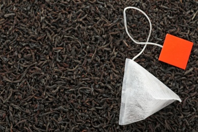 Photo of Tea bag on dry leaves, top view with space for text