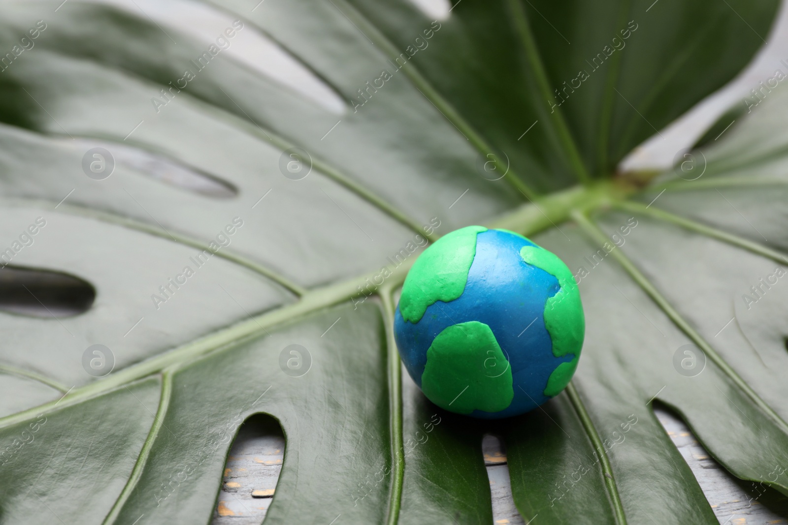 Photo of Happy Earth Day. Planet made of plasticine on green leaf, space for text