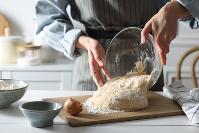 Photo of Woman kneading dough at white wooden table in kitchen, closeup