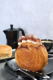 Photo of Round croissants with cream and chocolate chips served on grey table. Tasty puff pastry