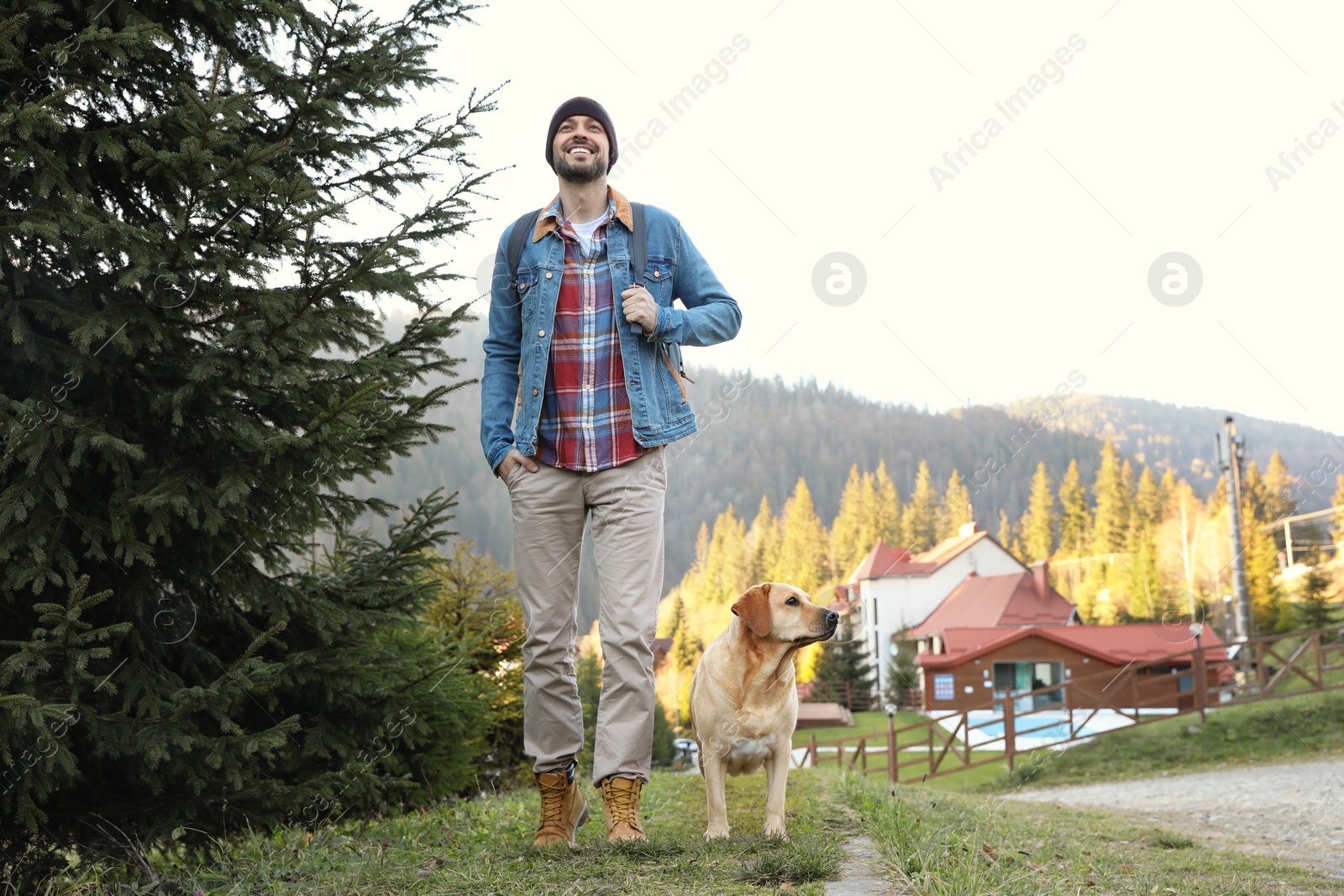 Photo of Happy man and adorable dog in mountains. Traveling with pet