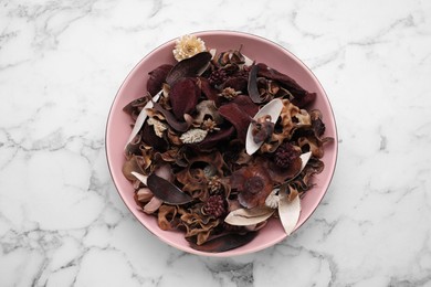 Photo of Aromatic potpourri of dried flowers in bowl on white marble table, top view