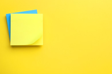 Paper notes on yellow background, top view. Space for text