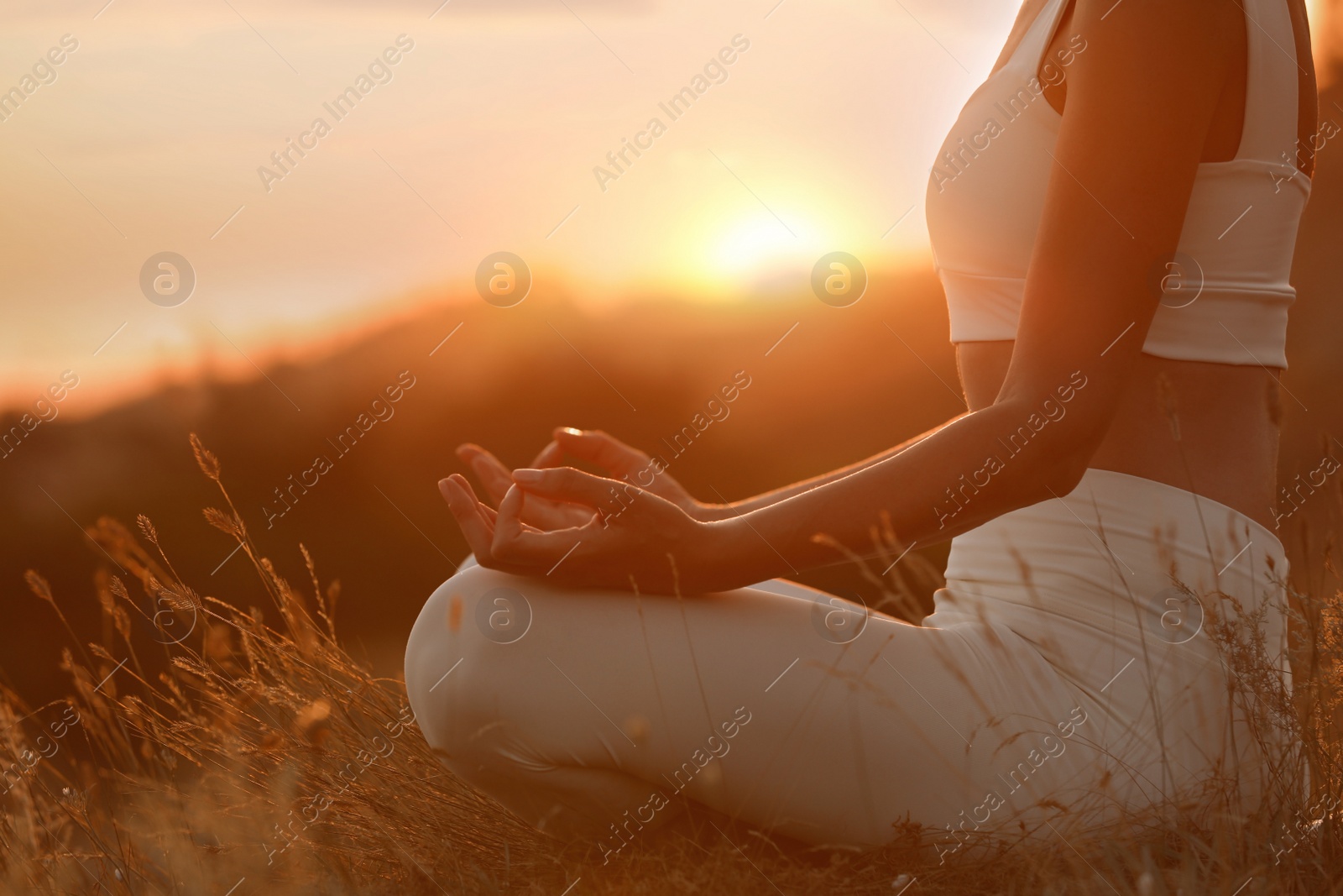 Photo of Woman meditating outdoors at sunset, closeup view