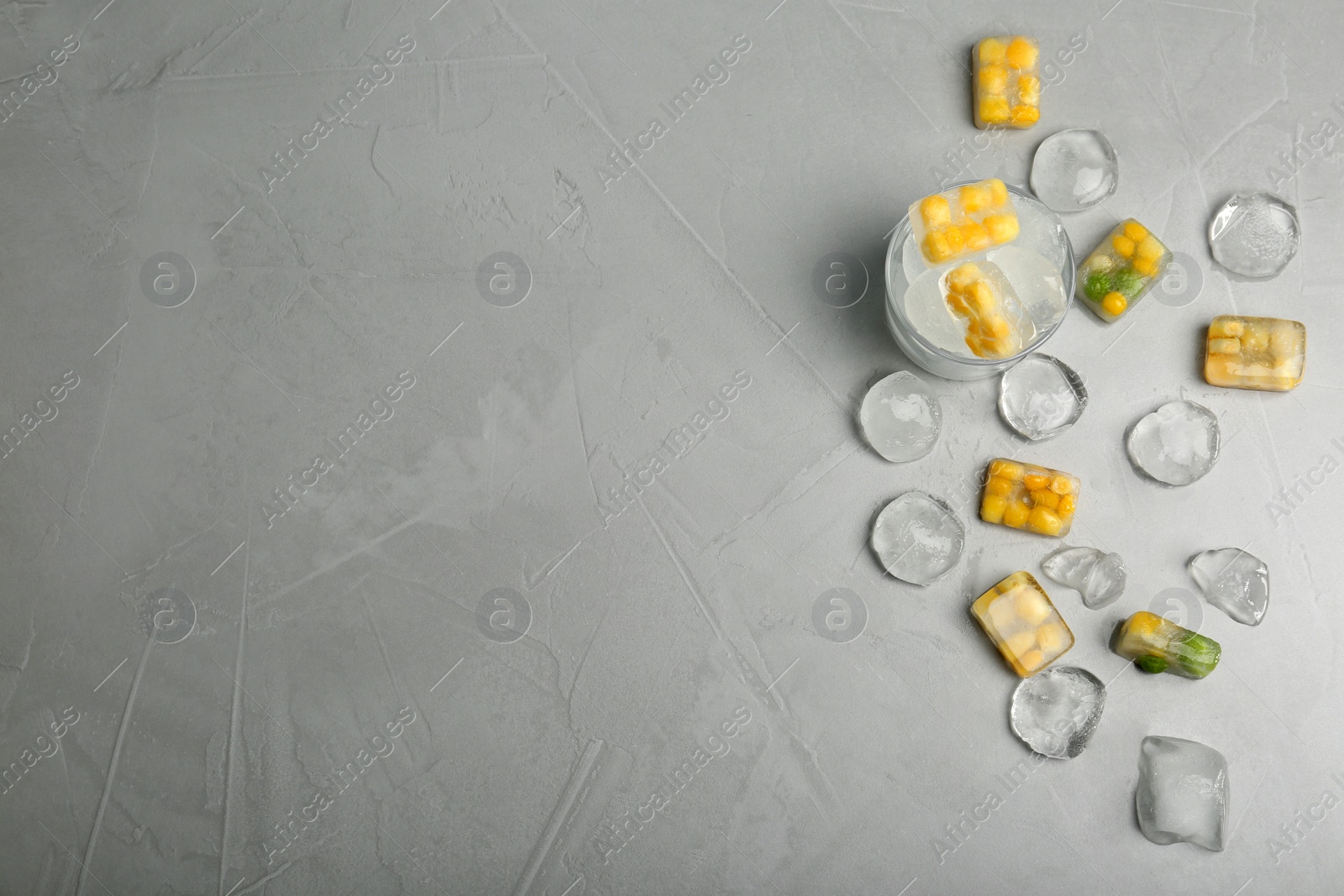 Photo of Frozen vegetables and ice cubes on gray background, flat lay composition with space for text